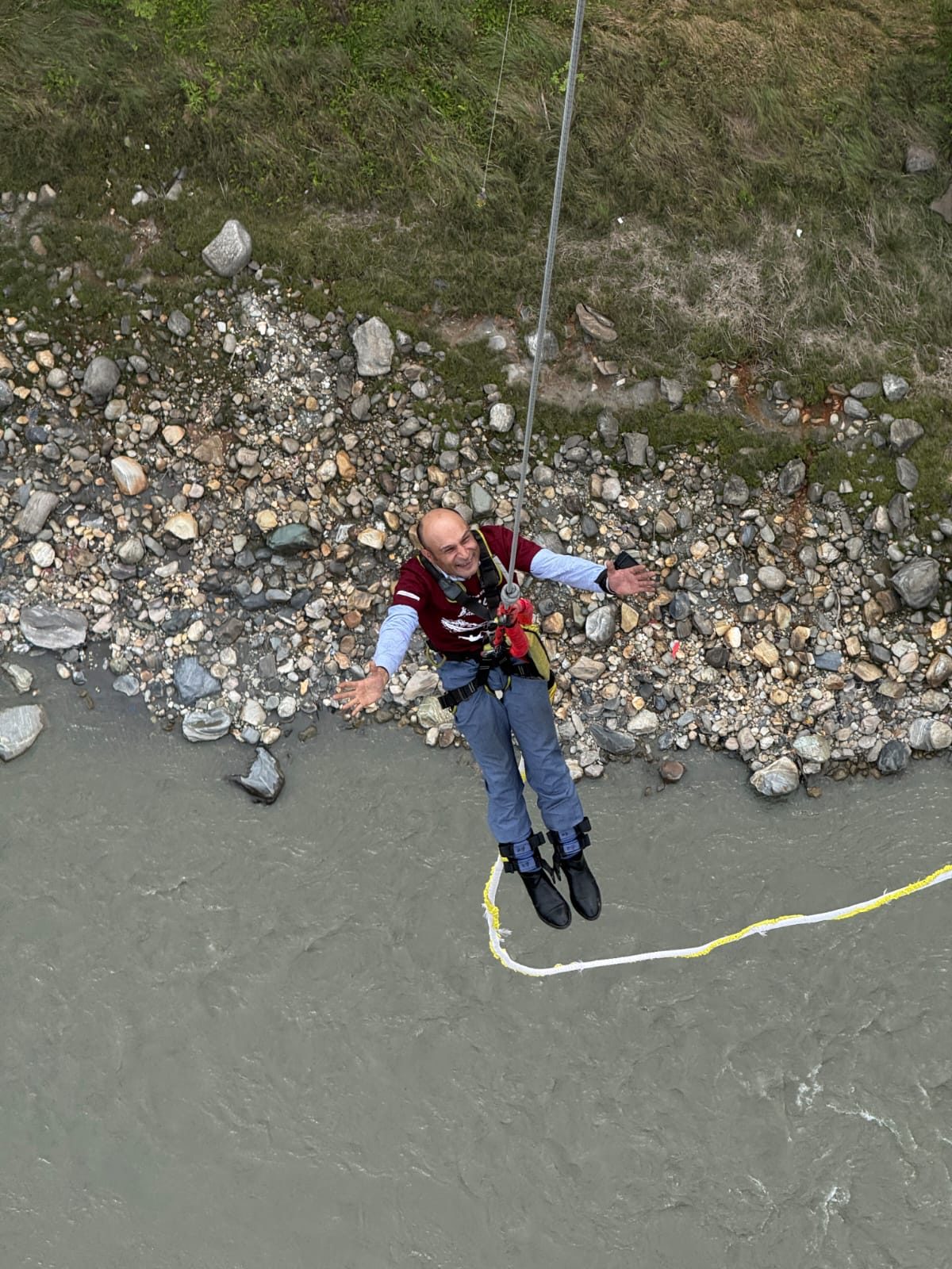 Santosh Sapkota — Nepal's first blind bungee jumper — mid-air over a river, arms outstretched